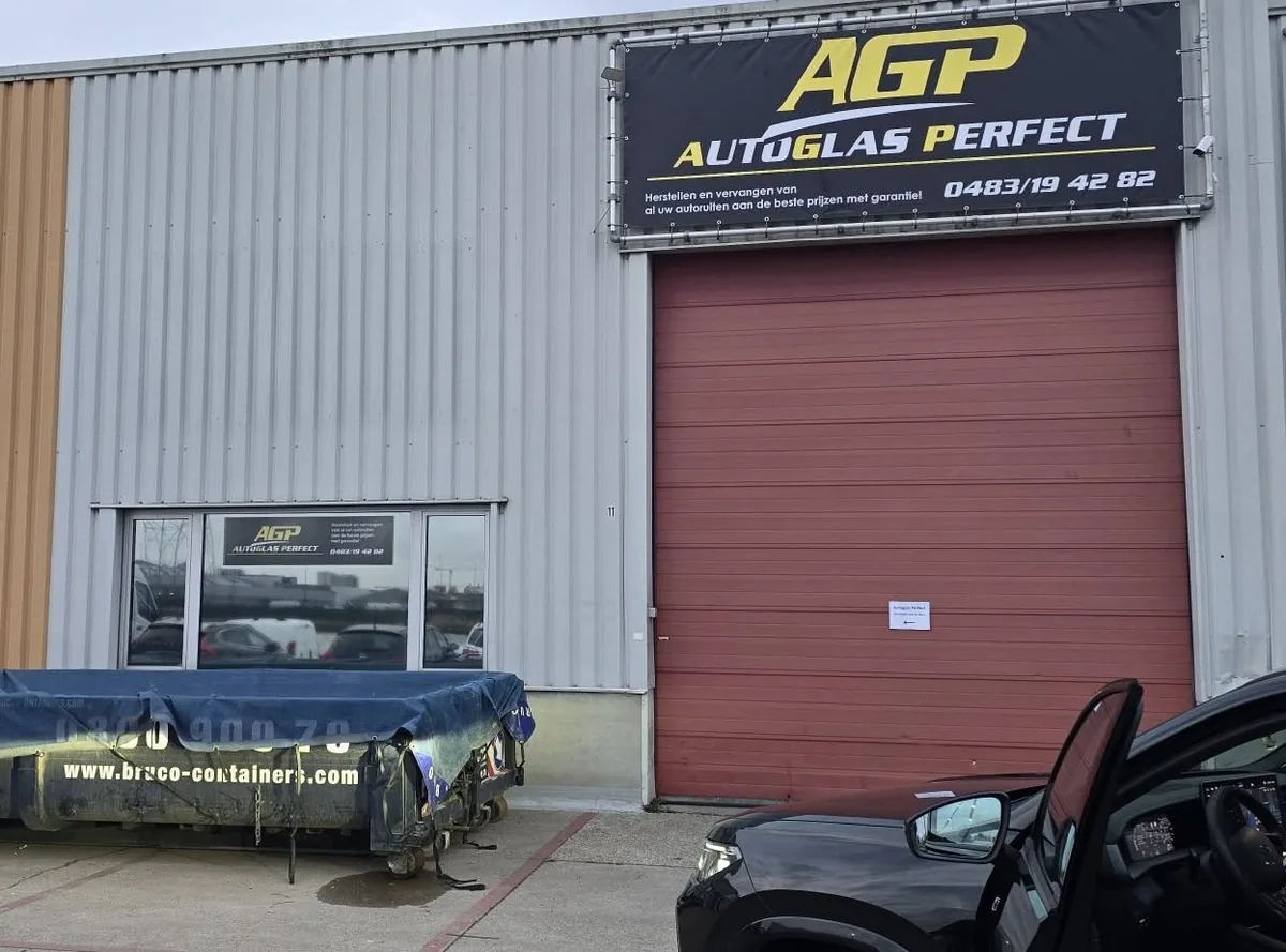 De werkplaats van Autoglas Perfect met het zwart-gele spandoek boven de poort
