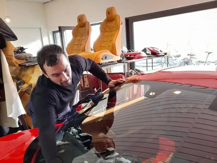 Twee monteurs werken samen aan de voorruit van de Ferrari