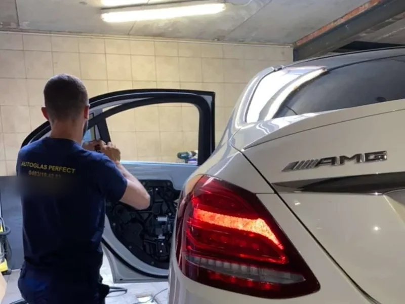 Monteur van Autoglas Perfect bij een witte Mercedes AMG