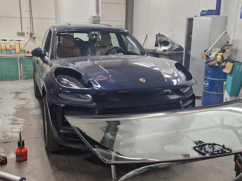Blauwe Porsche Cayenne met de uitgenomen ruit ernaast