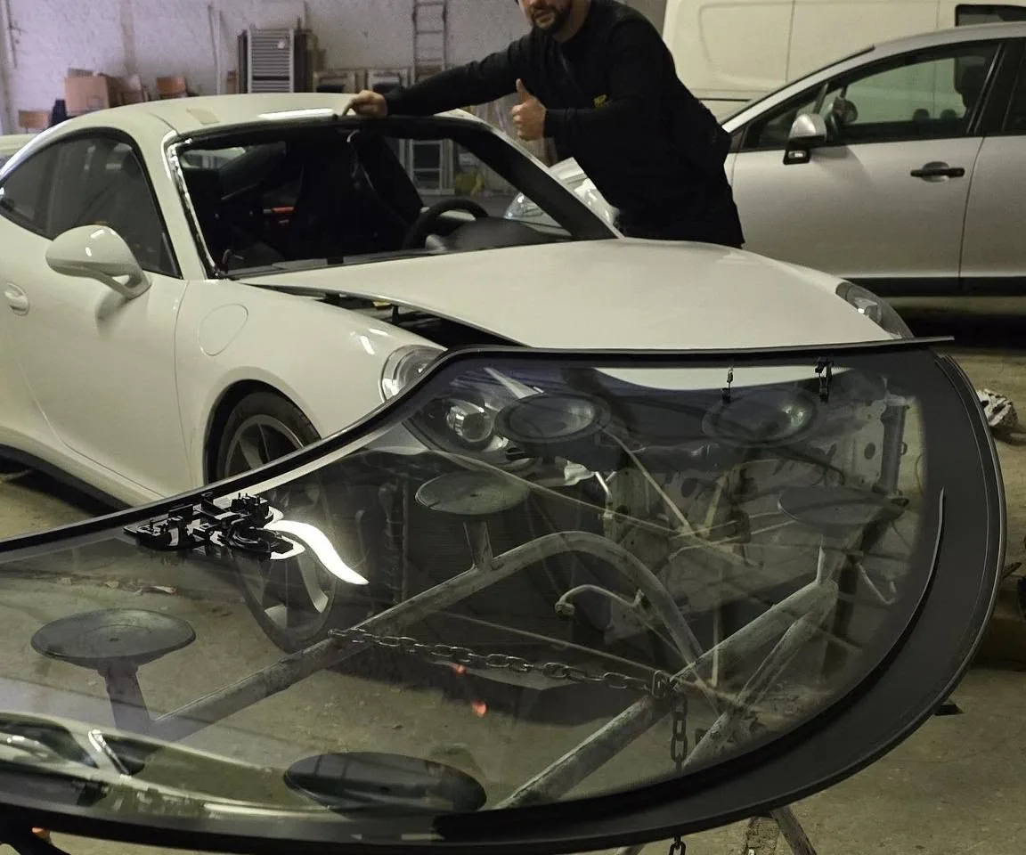 De voorruit van een Porsche 911 op een bok met zuignappen, klaar om geplaatst te worden
